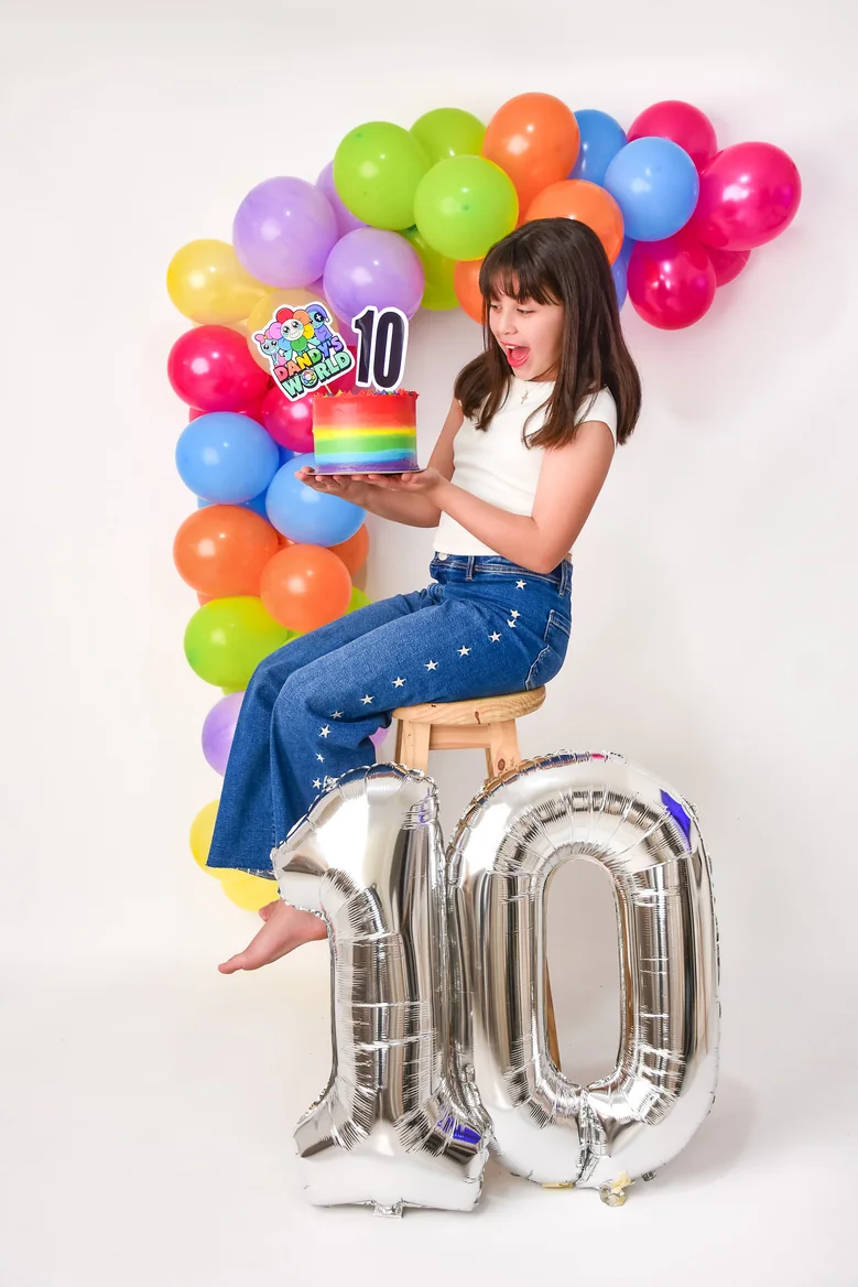 Nena sentada sobre globos con forma de número en su sesión pre cumple